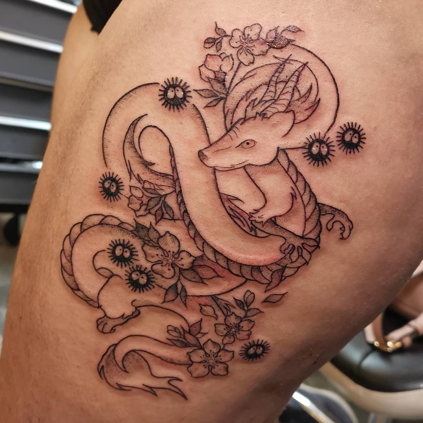 Tattoo of a fox among flowers and vines on the thigh